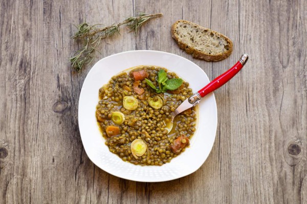 Letils stew ready o eat on a wooden table, seen from above.