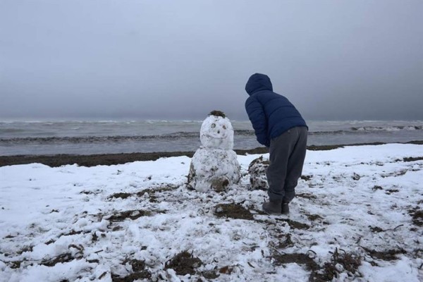 Un niño juega con un muñeco de nieve en la playa de Les Marines, en Denia, completamente nevada desde primeras horas de la mañana. EFE