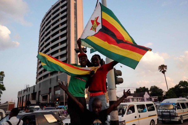 TOPSHOT - People and soldiers celebrate after the resignation of Zimbabwe's president Robert Mugabe on November 21, 2017 in Harare.Car horns blared and cheering crowds raced through the streets of the Zimbabwean capital Harare as news spread that President Robert Mugabe, 93, had resigned after 37 years in power. / AFP PHOTO / Marco Longari