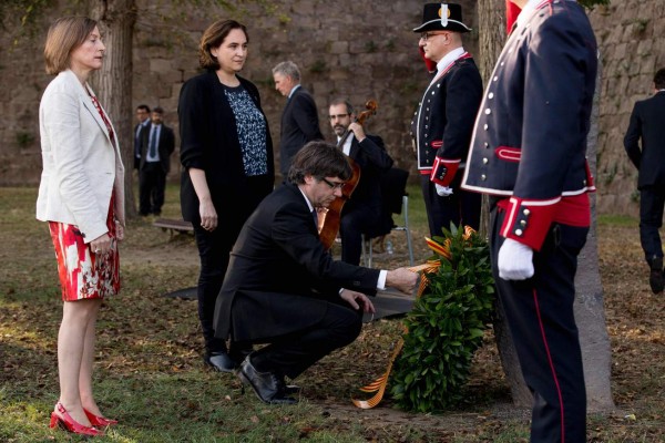 Catalan regional government president Carles Puigdemont (C) lays a wreath next to Catalan parliament president Carme Forcadell (L) and Barcelona mayor Ada Colau (2nd-L) during a ceremony commemorating the 77th anniversary of the death of Catalan leader Lluis Companys at the Montjuic Castle in Barcelona on October 15, 2017.Companys had proclaimed a 'Catalan state in the Spanish federal republic' in 1934 to oppose the conservatives who governed in Madrid. Exiled in France, Companys was denounced by the Nazis in 1940 and handed over to Spain where he was executed. / AFP PHOTO / PAU BARRENA