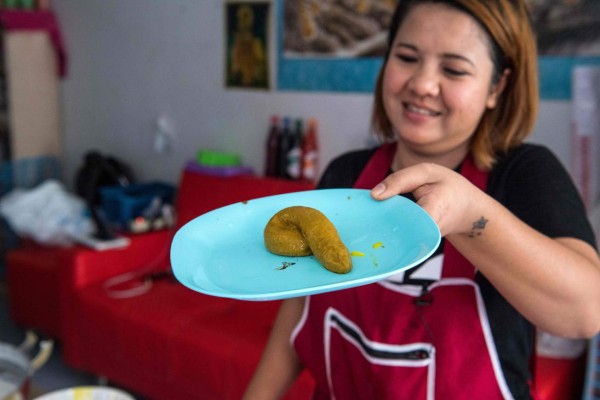 This picture taken on June 19, 2017 shows Wilaiwan Mee-Nguen showing off a dessert in the shape of dog poop that she prepared at her home in Bangkok.It might turn some stomachs, but a dessert-maker in Thailand has been flooded with orders ever since she started crafting gelatinous sweets into the shape -- and colour -- of dog poop. / AFP PHOTO / Roberto SCHMIDT