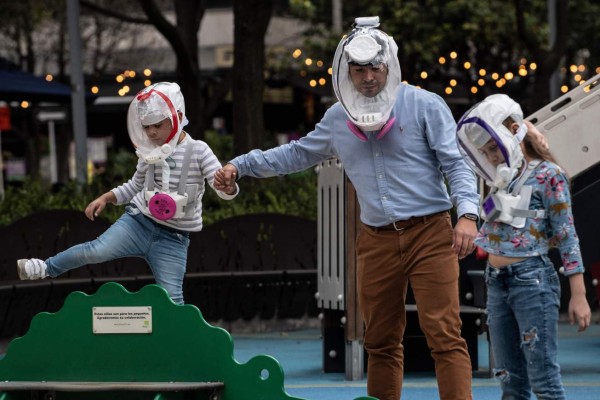 A man and his children wear ventilation masks against the spread of the COVID-19 coronavirus pandemic at a park in Bogota on October 9, 2020. (Photo by Juan BARRETO / AFP)