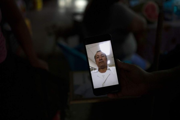 Salvadoran Raquel Eunice Barrera, 28, shows a picture of her brother Jesus Barrera, 52, a nurse that recently died of COVID-19, along with four other relatives in Santiago Nonualco, La Paz department, El Salvador on July 23, 2020. - 'The world is infested and there is fear, in my family there have been five deaths in a short time and it has been hard to lose them like that,' says Raquel Barrera, a Salvadoran who saw her two parents and three siblings die in less than two months from COVID-19. (Photo by Yuri CORTEZ / AFP)