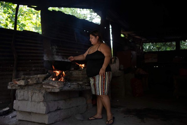Salvadoran Raquel Eunice Barrera, 28, cooks at her house in Santiago Nonualco, La Paz department, El Salvador on July 23, 2020. - 'The world is infested and there is fear, in my family there have been five deaths in a short time and it has been hard to lose them like that,' says Raquel Barrera, a Salvadoran who saw her two parents and three siblings die in less than two months from COVID-19. (Photo by Yuri CORTEZ / AFP)