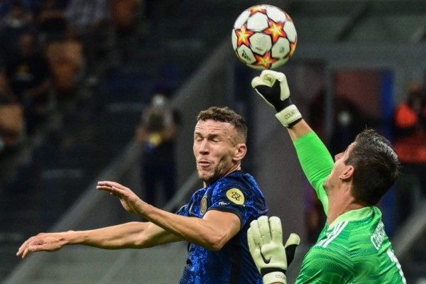 Real Madrid's Belgian goalkeeper Thibaut Courtois (R) deflects a shot under pressure from Inter Milan's Croatian midfielder Ivan Perisic during the UEFA Champions League Group D football match between Inter Milan and Real Madrid on September 15, 2021 at the San Siro stadium in Milan. (Photo by MIGUEL MEDINA / AFP)