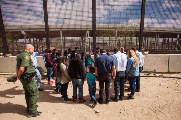 EL PASO, TX - MARCH 28: A group of evangelical pastors pray with a group of 22 migrants from Honduras, Guatemala and Salvador underneath the Paso Del Norte Bridge where they are being held for processing on March 28, 2019 in El Paso, Texas. U.S. Customs and Border Protection has temporarily closed all highway checkpoints along the 268-mile stretch of border in the El Paso sector to try to stem a surge in illegal entry. Christ Chavez/Getty Images/AFP== FOR NEWSPAPERS, INTERNET, TELCOS & TELEVISION USE ONLY ==