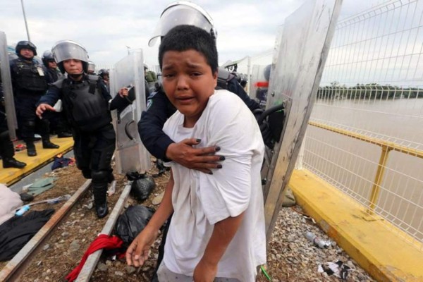 Una mujer policía sujeta al niño Mario Castellanos en la frontera de México.