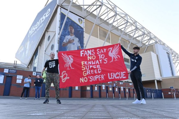 Leeds United fans hold a banner against plans for a European Super League and the involvement of Liverpool football club outside Elland Road ahead of the English Premier League football match between Leeds United and Liverpool in Leeds, northern England, on April 19, 2021. - Twelve of Europe's biggest clubs on Monday said they planned to launch a breakaway Super League, despite the threat of an international ban for them and their players. 'AC Milan, Arsenal, Atletico Madrid, Chelsea, Barcelona, Inter Milan, Juventus, Liverpool, Manchester City, Manchester United, Real Madrid and Tottenham Hotspur have all joined as founding clubs,' said a statement by the group. (Photo by Paul ELLIS / AFP)