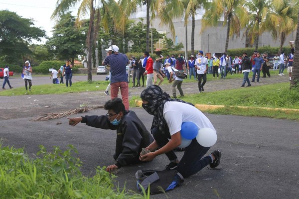 Nicaragua's anti-government protestors clash against riot police after attending a mass to celebrate the release of political prisoners at the Managua Cathedral, in Managua on June 16, 2019. (Photo by Maynor Valenzuela / AFP)