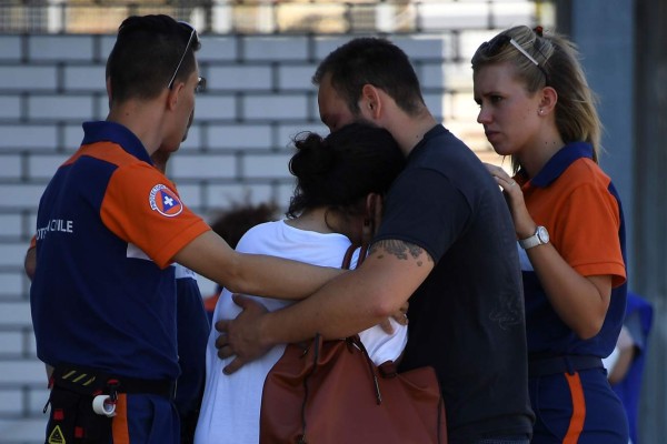 Protection civil agents try to comfort people hugging each other outside Pasteur hospital in the French riviera town of Nice on July 17, 2016, after the July 14 truck attack that killed 84 people in Nice on France's national holiday.The Islamic State group claimed responsibility for the truck attack that killed 84 people in Nice on France's national holiday, a news service affiliated with the jihadists said on July 16. Tunisian Mohamed Lahouaiej-Bouhlel, 31, smashed a 19-tonne truck into a packed crowd of people in the Riviera city celebrating Bastille Day -- France's national day. / AFP PHOTO / ANNE-CHRISTINE POUJOULAT