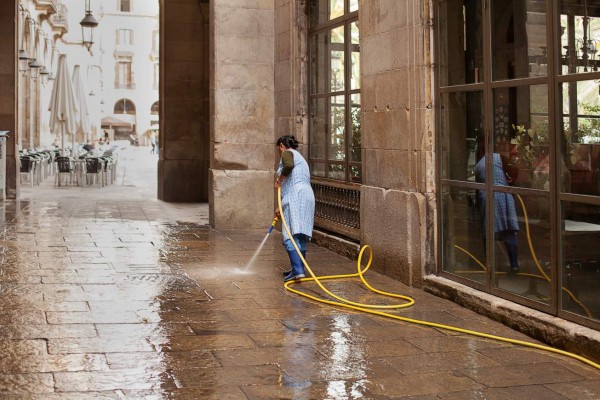 Barcelona, Spain-May 27, 2013. Female worker hosing down footpath near the Plaza Real, Barcelona, Spain