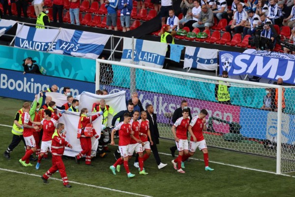 Players escort paramedics as Denmark's midfielder Christian Eriksen is evacuated from the pitch during the UEFA EURO 2020 Group B football match between Denmark and Finland at the Parken Stadium in Copenhagen on June 12, 2021. (Photo by WOLFGANG RATTAY / various sources / AFP)