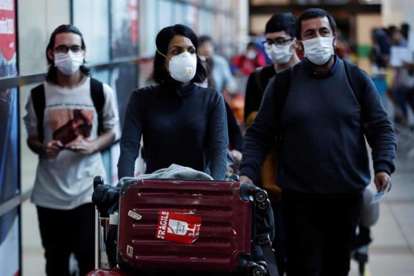Pasajeros son vistos usando mascarillas para evitar la propagación y el contagio del coronavirus el 11 de marzo de 2020, en el aeropuerto Arturo Merino Benítez, en Santiago, Chile. EFE/Alberto Valdes