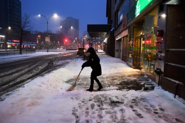 A woman cleans snow from her store front during a snowstorm in New York on March 14, 2017. Winter Storm Stella unleashed its fury on much of the northeastern United States on March 14 dropping snow and sleet across the region and leading to school closures and thousands of flight cancellations. Stella, the most powerful winter storm of the season, was forecast to dump up to two feet (60 centimeters) of snow in New York and whip the area with combined with winds of up to 60 miles per hour (95 kilometers per hour), causing treacherous whiteout conditions. / AFP PHOTO / Jewel SAMAD