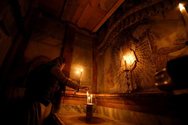 A picture taken at the Church of the Holy Sepulchre in Jerusalems old city on March 20, 2017, shows a Christian worshipper praying inside the Edicule surrounding the Tomb of Jesus (where his body is believed to have been laid). / AFP PHOTO / Gali TIBBON