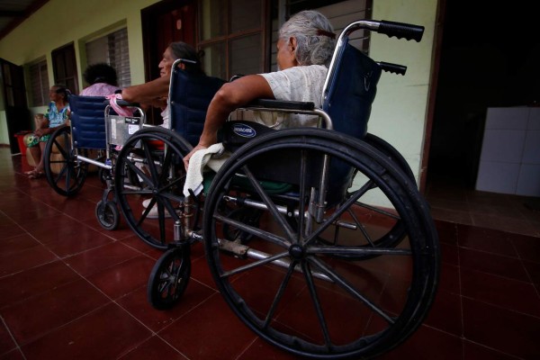Elderly people on wheelchairs wait to get medical assistance at Italian priest Ferdinando Castriotti's foundation in El Paraiso, Honduras, in the border with Nicaragua, on October 20, 2019. - Castriotti trains deportees to facilitate their social insertion. (Photo by STR / AFP)