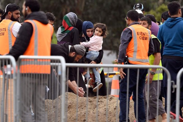 Relatives of Pakistni origin Syed Jahandad Ali, victim of New Zealand twin mosque attack, stays at his grave after burial at the Memorial Park cemetery in Christchurch on March 22, 2019. - The Muslim call to prayer will be broadcast across New Zealand on Friday as the nation pauses to mark a week since a heavily armed white supremacist stormed two mosques in a murder spree streamed online. (Photo by William WEST / AFP)