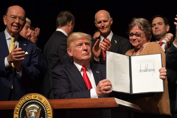 US President Donald Trump holds up a memorandum he signed on the US/ Cuba policy after he spoke at the Manuel Artime Theater in Miami, Florida on June 16, 2017. / AFP PHOTO / MANDEL NGAN