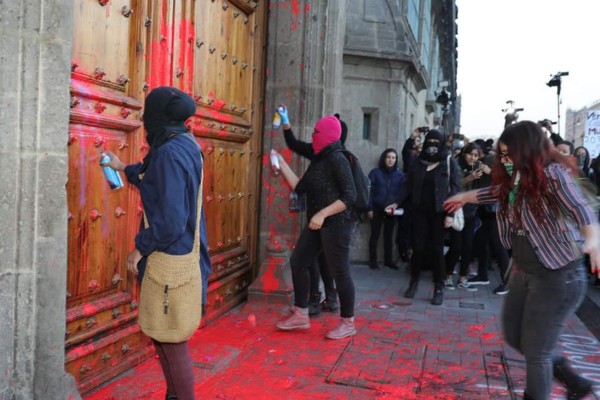 Mujeres pintan fachada y puerta de Palacio Nacional por feminicidio en México