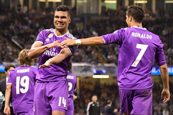 Real Madrid's Brazilian midfielder Casemiro (L) celebrates with Real Madrid's Portuguese striker Cristiano Ronaldo after scoring their second goal during the UEFA Champions League final football match between Juventus and Real Madrid at The Principality Stadium in Cardiff, south Wales, on June 3, 2017. / AFP PHOTO / JAVIER SORIANO