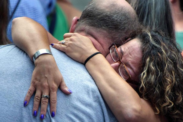 People embrace during a memorial service at the National 9/11 Memorial September 11, 2016 in New York.The United States on Sunday commemorated the 15th anniversary of the 9/11 attacks. / AFP PHOTO / Brendan Smialowski