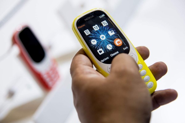 A person tests the new 'Nokia 3310' model of Finnish HMD global at the Mobile World Congress on the first day of the MWC in Barcelona, on February 27, 2017.Phone makers will seek to seduce new buyers with artificial intelligence functions and other innovations at the world's biggest mobile fair starting today in Spain. / AFP PHOTO / Josep Lago