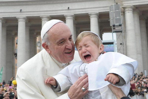 El papa Francisco besa a un niño vestido de Pontífice