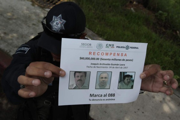 ACOMPAÑA CRÓNICA: MÉXICO NARCOTRÁFICO. MEX06. ALMOLOYA (MÉXICO), 16/07/2015.- Un policía muestra un aviso de recompensa hoy, jueves 16 de julio de 2015, mientras se adelantan investigaciones en la casa donde se construyó el túnel por el que escapó el narcotraficante Joaquín 'El Chapo' Guzmán de su celda de la cárcel Altiplano I, en el municipio de Almoloya del céntrico Estado de México. Rodeada de campos y algunas viviendas muy alejadas entre sí se halla la casa desde donde se construyó el túnel de un kilómetro y medio que permitió la huida el pasado sábado de 'El Chapo' Guzmán del penal de máxima seguridad donde estaba recluido. La construcción se conforma de una vivienda con algunas recámaras y de una suerte de bodega (almacén), desde donde se entra a este túnel que llega a más de diez metros de profundidad y se extiende 1,5 kilómetros hasta llegar, con una perfección milimétrica, a la regadera (ducha) de la celda donde estaba recluido el capo tras su detención en febrero de 2014. EFE/Alex Cruz