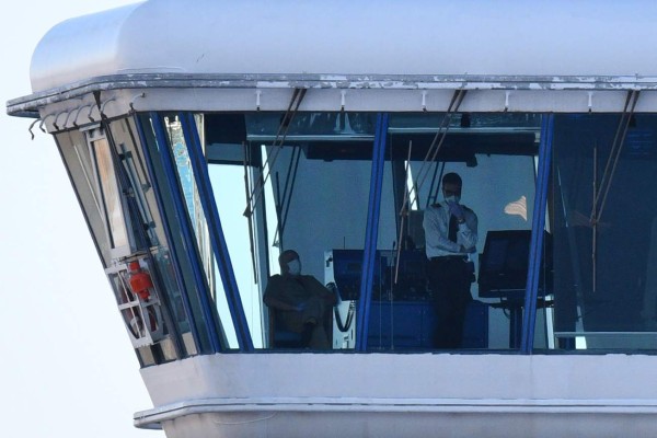 Crew members aboard the Diamond Princess cruise ship are seen at its wheelhouse at the Daikoku Pier Cruise Terminal in Yokohama port on February 27, 2020. - Crew members from a coronavirus-stricken cruise ship off Japan began leaving the vessel February 27 for a new quarantine on-shore after passengers left the boat, the government said, as one new death was reported in northern Hokkaido. (Photo by Kazuhiro NOGI / AFP)