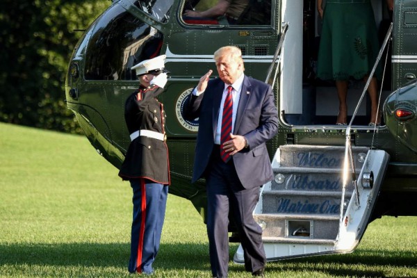 US President Donald Trump salutes a soldier as he steps out of Marine One, returning to the White House after two weeks spent at his golf club in New Jersey on August 18, 2019 in Washington, DC. (Photo by Eric BARADAT / AFP)