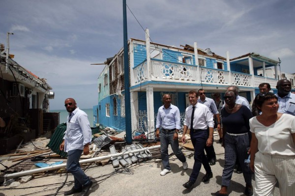 French President Emmanuel Macron (R) walks with residents during a visit to the French Caribbean island of St. Martin on September 12, 2017. French President Emmanuel Macron and British Foreign Secretary Boris Johnson travelled to the hurricane-hit Caribbean, rebuffing criticism over the relief efforts as European countries boost aid to their devastated island territories. Macron's plane touched down in St Martin as anger grew over looting and lawlessness in the French-Dutch territory after Hurricane Irma. / AFP PHOTO / POOL / Christophe Ena