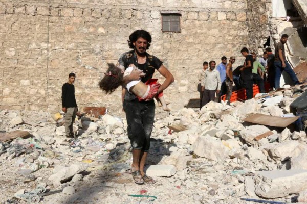 Un hombre carga a una niña herida tras un bombardeo en una región controlada por el Isis.