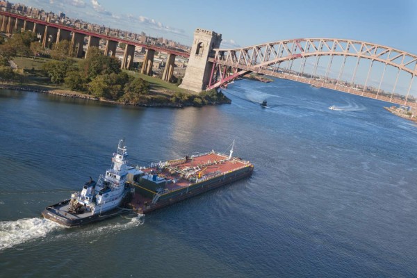 New York City, USA - September 28, 2013: A large ship is ready to go through the Hell Gate Bridge. The Hell Gate Bridge is a 1,017-foot (310 m) steel through arch railroad bridge between Astoria in the borough of Queens, Randall's/Wards Island (which are now joined into one island and are politically part of Manhattan), and The Bronx in New York City, over a portion of the East River known as Hell Gate.