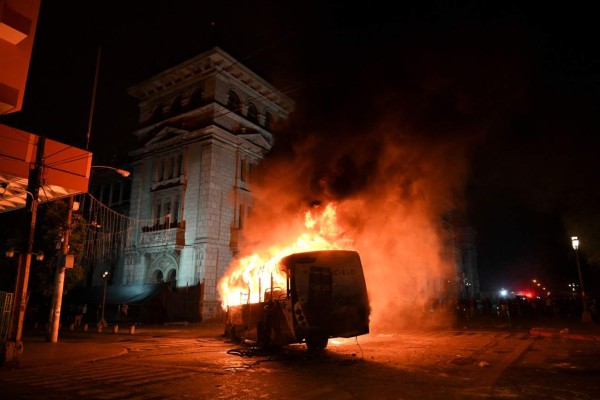 TOPSHOT - Demonstrators set a bus on fire during a protest demanding the resignation of Guatemalan President Alejandro Giammattei, in Guatemala City on November 28, 2020. (Photo by Johan ORDONEZ / AFP)