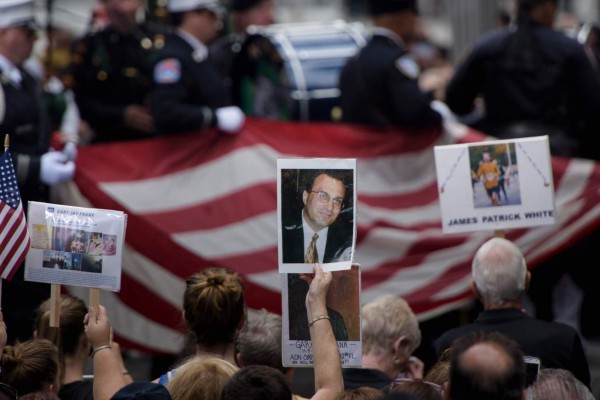 People hold up photos of victims during a memorial service at the 9/11 memorial September 1, 2016 in New York.The United States on Sunday commemorated the 15th anniversary of the 9/11 attacks. / AFP PHOTO / Brendan Smialowski