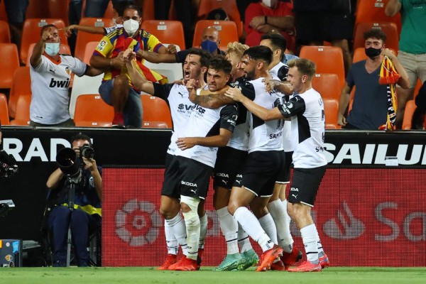 Valencia players celebrate the opening goal scored by Valencia's Spanish forward Hugo Duro during the Spanish League football match between Valencia CF and Real Madrid CF at the Mestalla stadium in Valencia on September 19, 2021. (Photo by JOSE JORDAN / AFP)