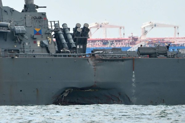 A general view shows the guided-missile destroyer USS John S. McCain with a hole on its left portside after a collision with oil tanker, outside Changi naval base in Singapore on August 21, 2017.Ten US sailors were missing and five injured early on August 21 after their destroyer collided with a tanker east of Singapore, the second accident involving an American warship in two months. / AFP PHOTO / ROSLAN RAHMAN