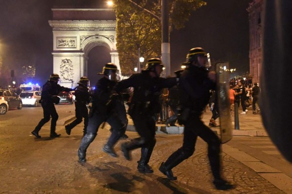 French CRS riot police intervene as Paris Saint-Germain supporters celebrate their team's 3-0 win over RB Leipzig at the Champs-Elysees Avenue near the Arc de Triomphe in Paris on late August 18, 2020 following the UEFA Champions League semi-final football match between Leipzig and Paris Saint-Germain, played in Lisbon. - Paris Saint-Germain are through to the final of the Champions League for the first time after goals by Marquinhos, Angel Di Maria and Juan Bernat saw them ease to a 3-0 win over RB Leipzig in a one-sided semi-final in Lisbon on August 18. (Photo by Bertrand GUAY / AFP)