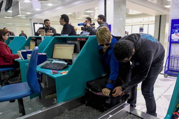 A Tunisian couple bound for London pack away their electronics in their luggage as they check-in for a flight at Tunis-Carthage International Airport on March 25, 2017.The United States this week announced a ban on all electronics larger than a standard smartphone on board direct flights out of eight countries across the Middle East, in effect from March 25, 2017. US officials would not specify how long the ban will last, but Emirates told AFP that it had been instructed to enforce the measures until at least October 14. Britain has also announced a parallel electronics ban targeting all flights out of Egypt, Turkey, Jordan, Saudi Arabia, Tunisia and Lebanon. / AFP PHOTO / FETHI BELAID