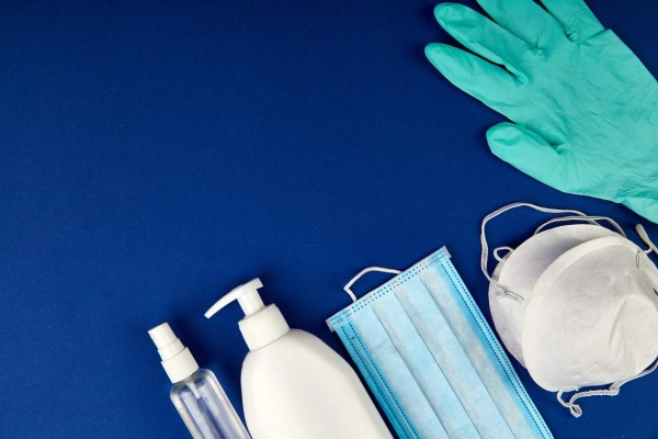 Flat lay of Coronavirus protection, medical protective masks, gloves, hand sanitizer bottles, antiseptic, disinfection, spray on blue background, copy space.