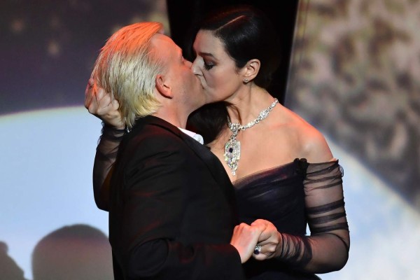 Italian actress and master of ceremonies Monica Bellucci (R) and French comedian Alex Lutz kiss as they perform on stage on May 17, 2017 during of the opening ceremony of the 70th edition of the Cannes Film Festival in Cannes, southern France. / AFP PHOTO / Alberto PIZZOLI