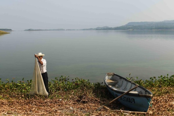 Pescadores y aves se disputan los peces en lago salvadoreño