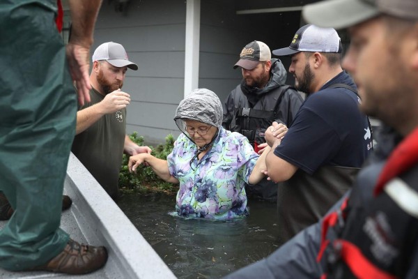 PORT ARTHUR, TX - AUGUST 30: Volunteer rescuer workers help a woman from her home that was inundated with the flooding of Hurricane Harvey on August 30, 2017 in Port Arthur, Texas. Harvey, which made landfall north of Corpus Christi late Friday evening, is expected to dump upwards to 40 inches of rain in Texas over the next couple of days. Joe Raedle/Getty Images/AFP== FOR NEWSPAPERS, INTERNET, TELCOS & TELEVISION USE ONLY ==