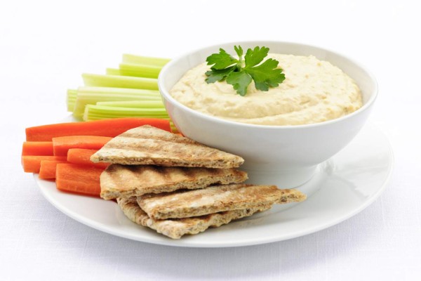 Healthy snack of hummus dip with pita bread slices and vegetables