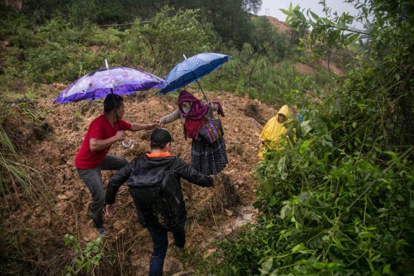 Pobladores cruzan a través de caminos improvisados por los derrumbes ocasionados por el paso de la depresión tropical Eta, hoy en Purulha (Guatemala). EFE/ Esteban Biba
