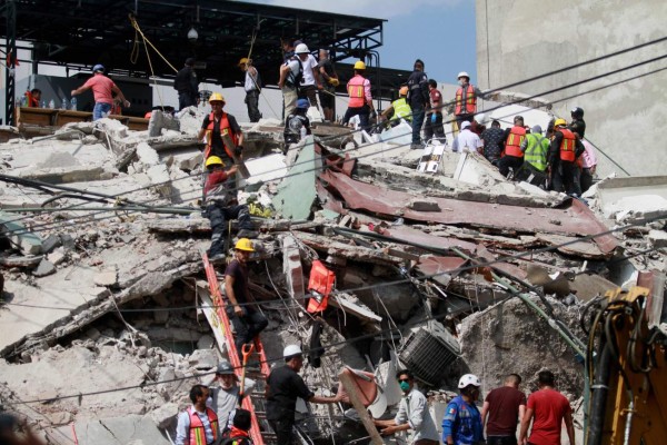 Rescuers and volunteers remove rubble and debris from a flattened building in search of survivors after a powerful quake in Mexico City on September 19, 2017.A powerful earthquake shook Mexico City on Tuesday, causing panic among the megalopolis' 20 million inhabitants on the 32nd anniversary of a devastating 1985 quake. The US Geological Survey put the quake's magnitude at 7.1 while Mexico's Seismological Institute said it measured 6.8 on its scale. The institute said the quake's epicenter was seven kilometers west of Chiautla de Tapia, in the neighboring state of Puebla. / AFP PHOTO / VICTOR CRUZ