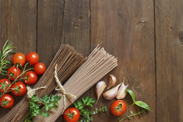 Three types of spaghetti, tomatoes and herbs on wood