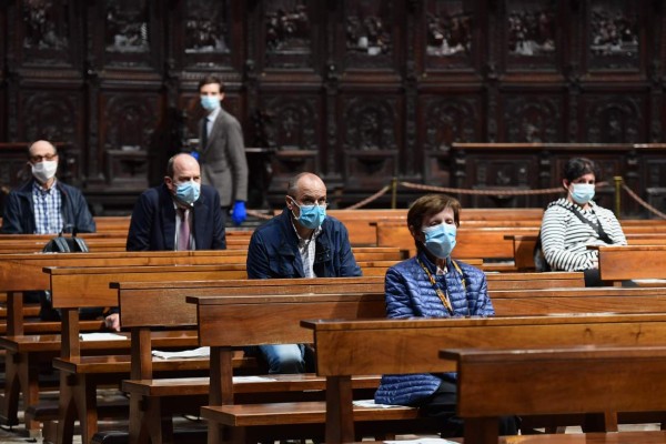 People attend a mass at the Cappella Feriale chapel of the Duomo cathedral in Milan on May 18, 2020 during the country's lockdown aimed at curbing the spread of the COVID-19 infection, caused by the novel coronavirus. - Restaurants and churches reopen in Italy on May 18, 2020 as part of a fresh wave of lockdown easing in Europe and the country's latest step in a cautious, gradual return to normality, allowing businesses and churches to reopen after a two-month lockdown. (Photo by Miguel MEDINA / AFP)