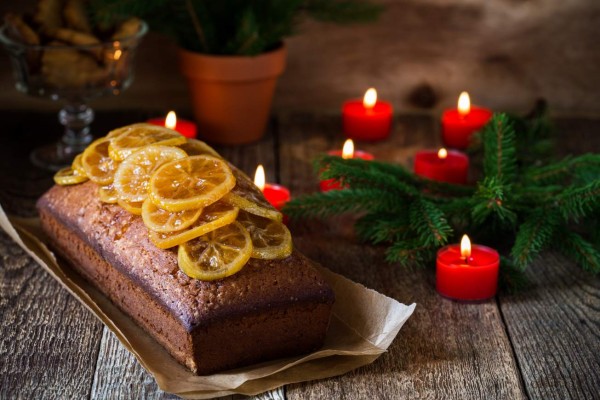 Homemade christmas lemon cake topped with candied fruits on rustic wooden table