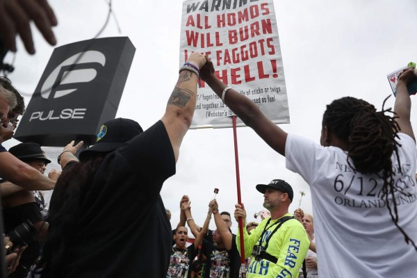 ORLANDO, FL - JUNE 12: Mourners circle around a man protesting against homosexuality with some chanting 'Love overcomes Hate' outside the Pulse gay nightclub as a memorial service was being held for the one-year anniversary of a mass shooting at the club on June 12, 2017 in Orlando, Florida. Omar Mateen killed 49 people and wounded 53 before being killed himself by police in a shootout at the club a little after 2 a.m. on June 12, 2016. Joe Raedle/Getty Images/AFP== FOR NEWSPAPERS, INTERNET, TELCOS & TELEVISION USE ONLY ==